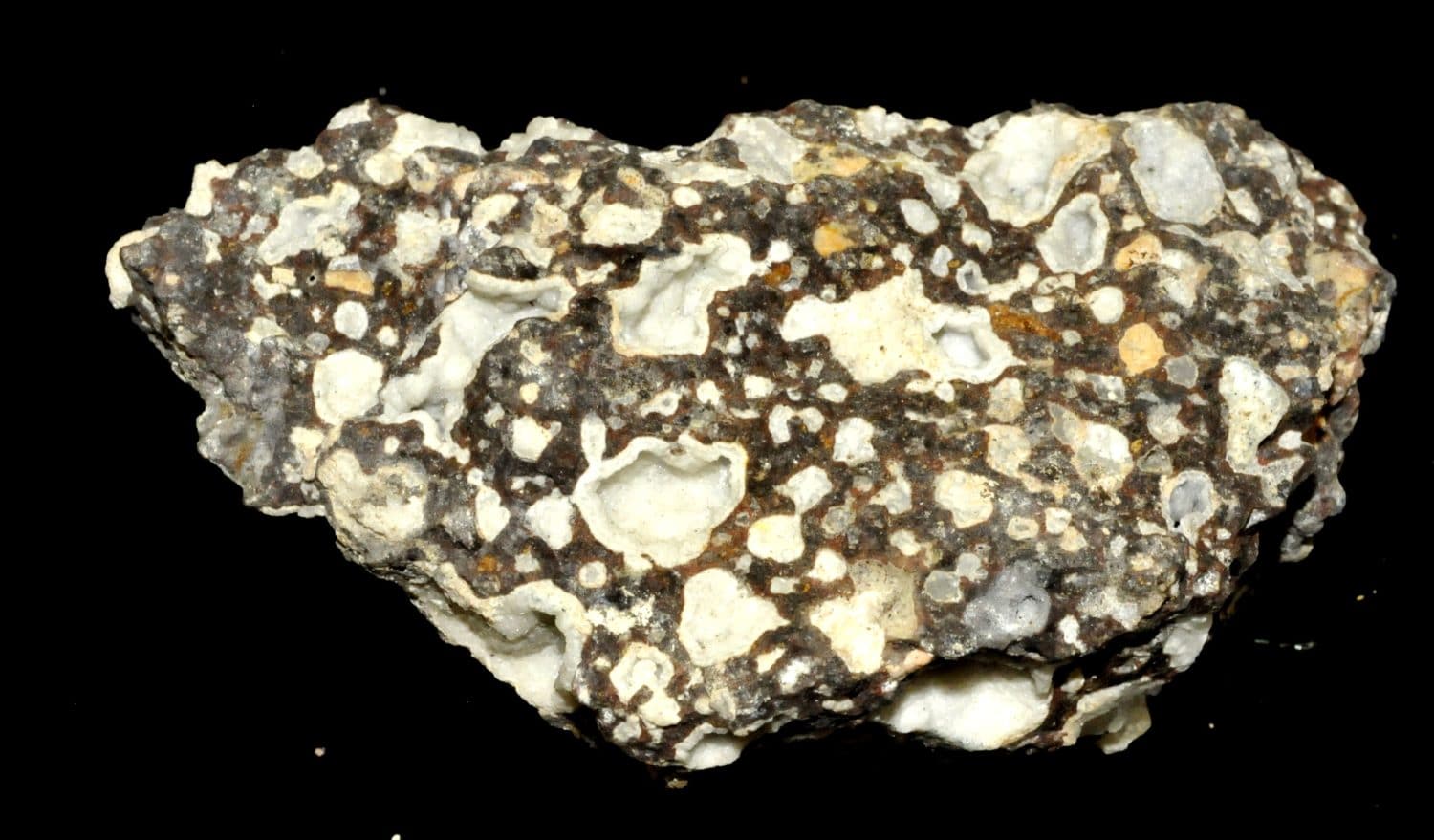 Roche volcanique avec de multiples géodes remplies de cristaux de gonnardite.